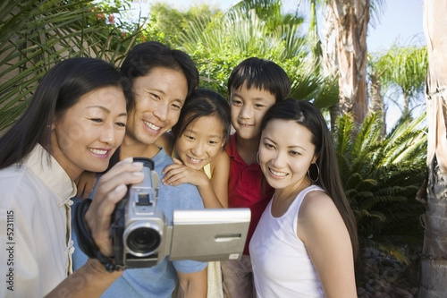 Photo: Family Looking at Video Camera Screen in back yard, front view Family Looking at Video Camera Screen in back yard, front view