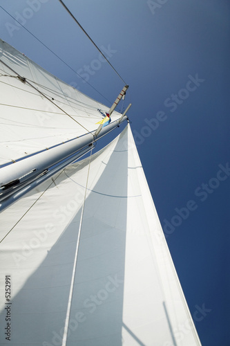 Photo: Sailboat mast and sail, low angle view Sailboat mast and sail, low angle view