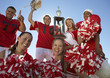 Photo: Football players and cheerleaders hoisting trophy, low angle view, portrait, portrait Football players and cheerleaders hoisting trophy, low angle view, portrait, portrait