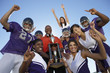 Photo: Football coach, players and cheerleaders holding trophy outside, low angle view, portrait, portrait Football coach, players and cheerleaders holding trophy outside, low angle view, portrait, portrait
