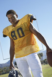 Photo: Football player holding helmet and ball standing on field, low angle view, portrait, portrait Football player holding helmet and ball standing on field, low angle view, portrait, portrait