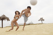 Woman Holding Man Back from Diving for Volleyball on Beach