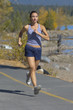 Woman running along road by woodland