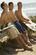 Photo: Three surfers leaning on bench holding surfboards on beach Three surfers leaning on bench holding surfboards on beach