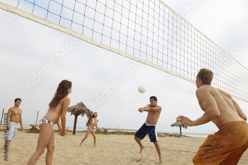 Photo: Man Hitting Volleyball during Game on Beach Man Hitting Volleyball during Game on Beach