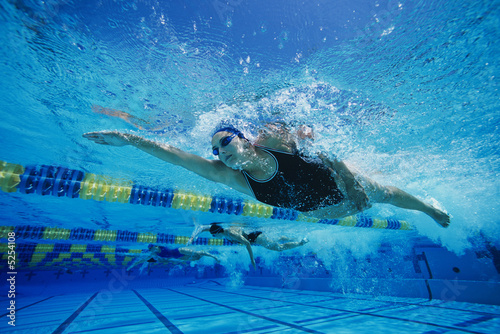 Photo: Female swimmers racing underwater in pool Female swimmers racing underwater in pool
