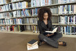 Young woman sitting on library floor, reading
