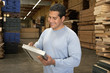 worker checking clipboard in warehouse of wood