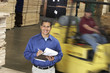 man with clipboard in front of forklift in warehouse