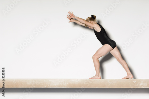Photo: Gymnast13-15 on balance beam preparing to do handstand, side view Gymnast13-15 on balance beam preparing to do handstand, side view