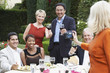 Photo: woman photographing friends celebrating with food and drink in garden woman photographing friends celebrating with food and drink in garden