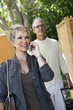 Mature woman using mobile phone walking through gate with husband