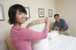 Couple making bed together, portrait