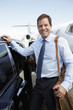 Photo: Smiling businessman standing beside car near private jet before Leaving on Business Trip Smiling businessman standing beside car near private jet before Leaving on Business Trip