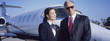 Businessman and Flight Crew Standing by Airplane