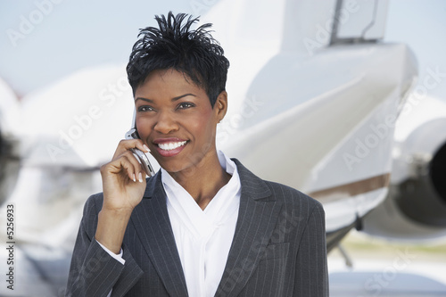 Foto: Smiling Businesswoman standing outside Airplane, talking on mobile Smiling Businesswoman standing outside Airplane, talking on mobile