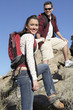 Young man helping young woman over rocks