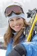 Photo: Woman holding skis in snow, head and shoulders, portrait. Woman holding skis in snow, head and shoulders, portrait.