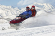 Photo: Couple driving snowmobile in front of snow covered mountains Couple driving snowmobile in front of snow covered mountains