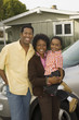 Couple with young boy standing by car in front of bungalow