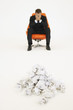 Frustrated businessman sitting near pile of crumpled paper