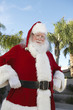 Smiling Santa Claus standing outside With Palm Trees
