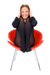 Happy girl seating on red chair and cover ears with hands