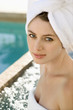 Photo: Woman wearing white robe smiling at viewer next to pool. Woman wearing white robe smiling at viewer next to pool.
