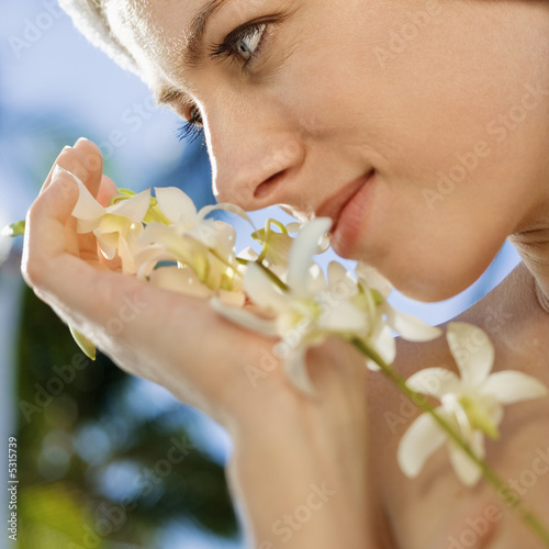 Photo: Woman holding white orchid flowers up to face. Woman holding white orchid flowers up to face.