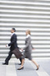 Businessman and businesswoman walking quickly, side view