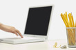 Pencils and sharpener by person using laptop, focus on foreground