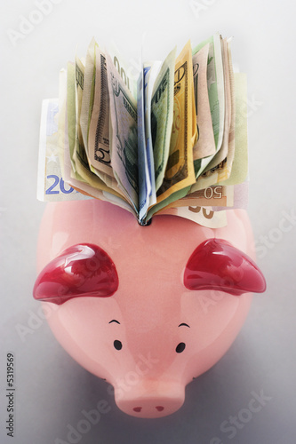Photo: Paper money coming out of piggy bank, view from above Paper money coming out of piggy bank, view from above