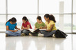 Preteen girls sitting on floor with schoolwork.