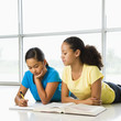 Photo: Two preteen girls lying on floor doing homework together. Two preteen girls lying on floor doing homework together.