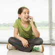 Photo: Caucasian preteen girl sitting on floor talking on cell phone. Caucasian preteen girl sitting on floor talking on cell phone.