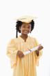 Foto: Girl in graduation robe and hat holding diploma and smiling. Girl in graduation robe and hat holding diploma and smiling.