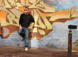 youth leans against graphiti wall youth leans against graphiti wall