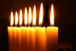 Eight burning candles over black background