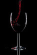 Red wine being poured into a glass splashing over the side.