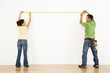 Couple measuring wall.
