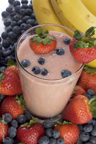 Smoothie surrounded by bananas, strawberries, and blueberries. Smoothie surrounded by bananas, strawberries, and blueberries.