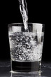 Pouring a clear liquid on a reflective tabletop