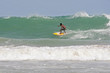 surfer tucks into a hollow wave on a beach in Phuket, Thailand