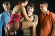 Three men standing in front of kneeling woman in dark room