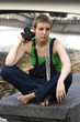 Sad young girl photographer sitting near the city river