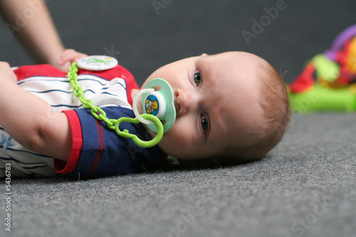Photo: Cute small kid lays on the grey background Cute small kid lays on the grey background