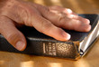 Hand On Well Used Old Bible Under Painted Light
