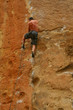 Bare back climber clinging to rock face,.. 
