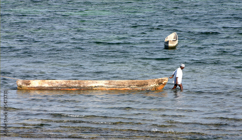 Photo: African man standing in water und pulling a boat African man standing in water und pulling a boat