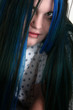 Young woman close up in hospital gown with blue and black hair.
